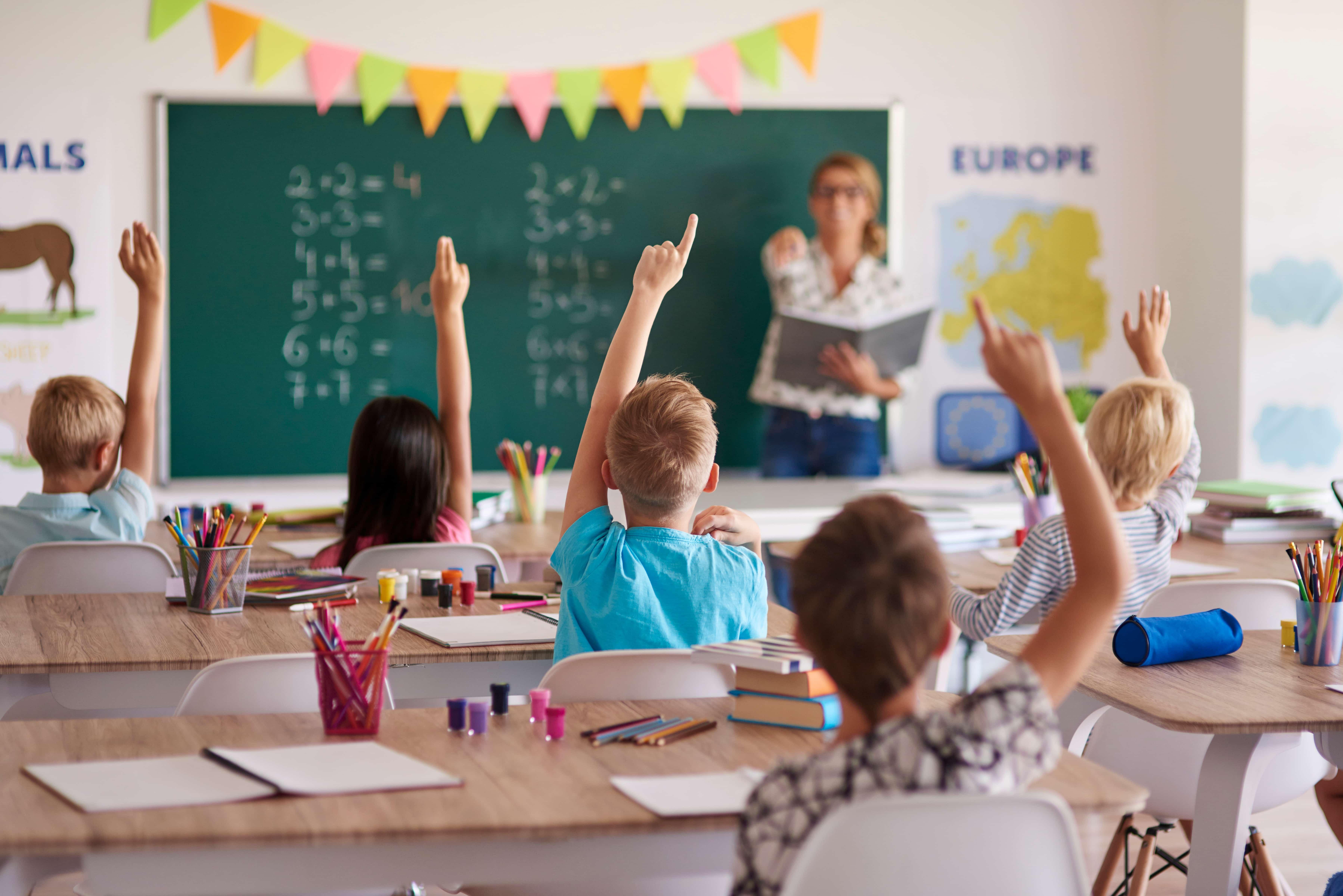 élèves levant la main dans une salle de classe